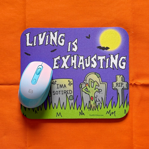 Mouse pad with cartoon design and text 'Living is Exhausting' on an orange surface.