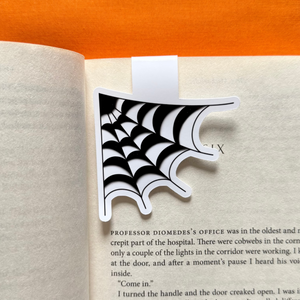 Black and white cobweb magnetic bookmark on an open book with an orange background