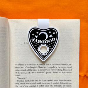 Ouija planchette magnetic bookmark on an open book with an orange background