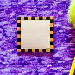 Small square sticky notepad with black and orange border on a purple textured background