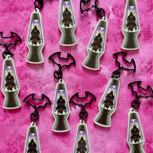 Lava lamp-shaped keychains with a haunted house design on a pink background with black bats clasps.