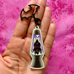Hand holding a keychain with a lava lamp design against a pink background